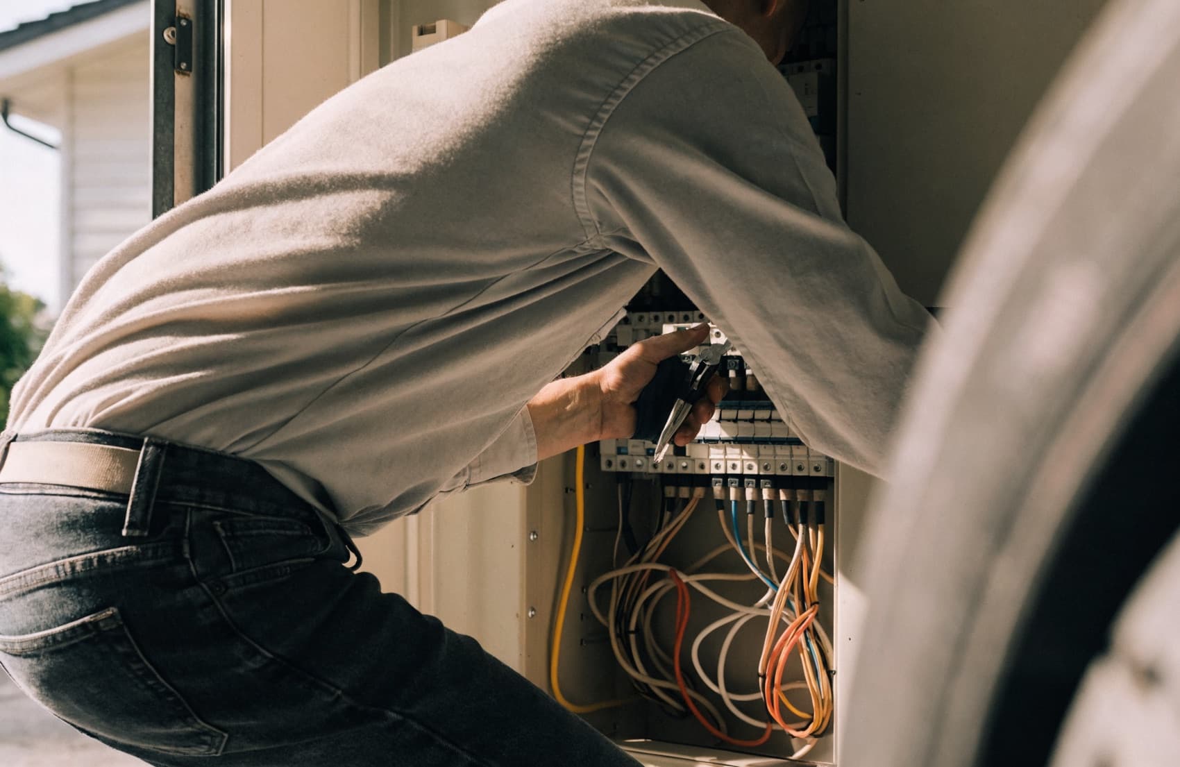 An electrician working on a residential panel upgrade while checking a phone for new job leads